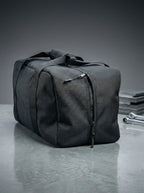 Black EQ1 Core Duffel bag with clean structure, spacious design, and travel-ready handles displayed on a white platform.
