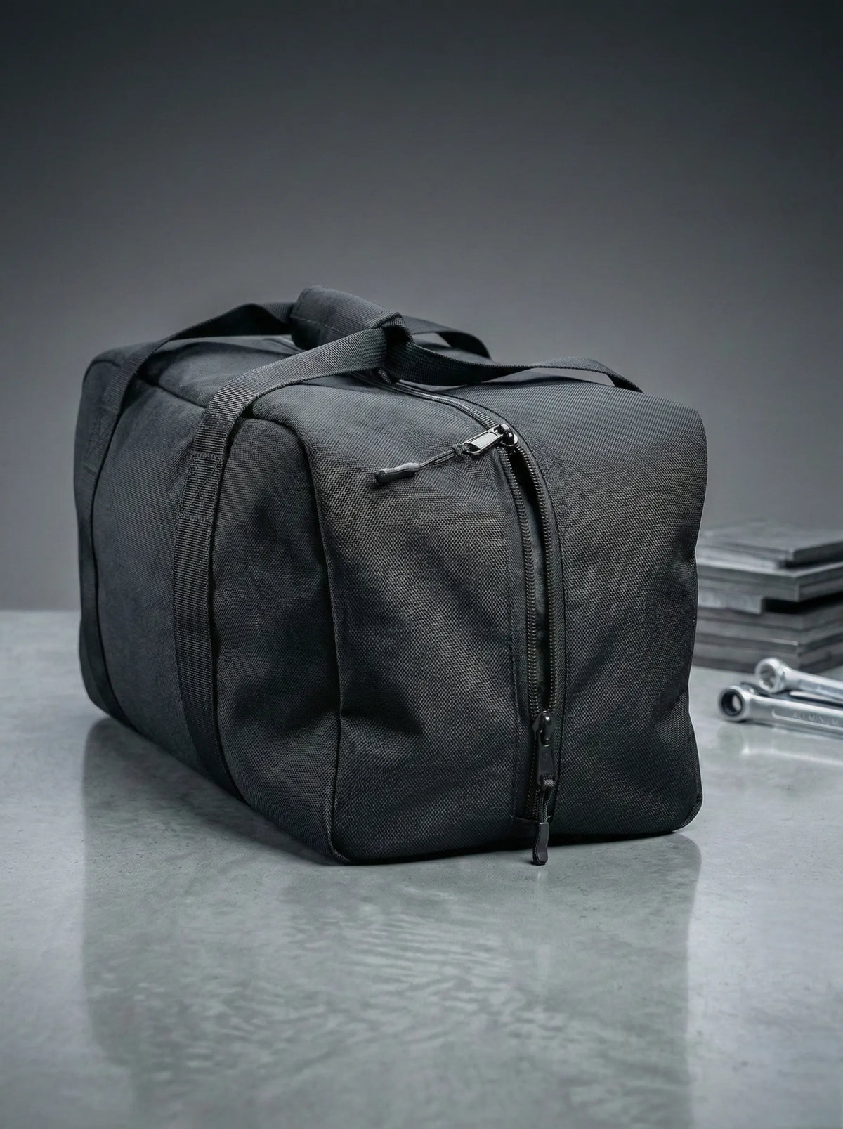 Black EQ1 Core Duffel bag with clean structure, spacious design, and travel-ready handles displayed on a white platform.
