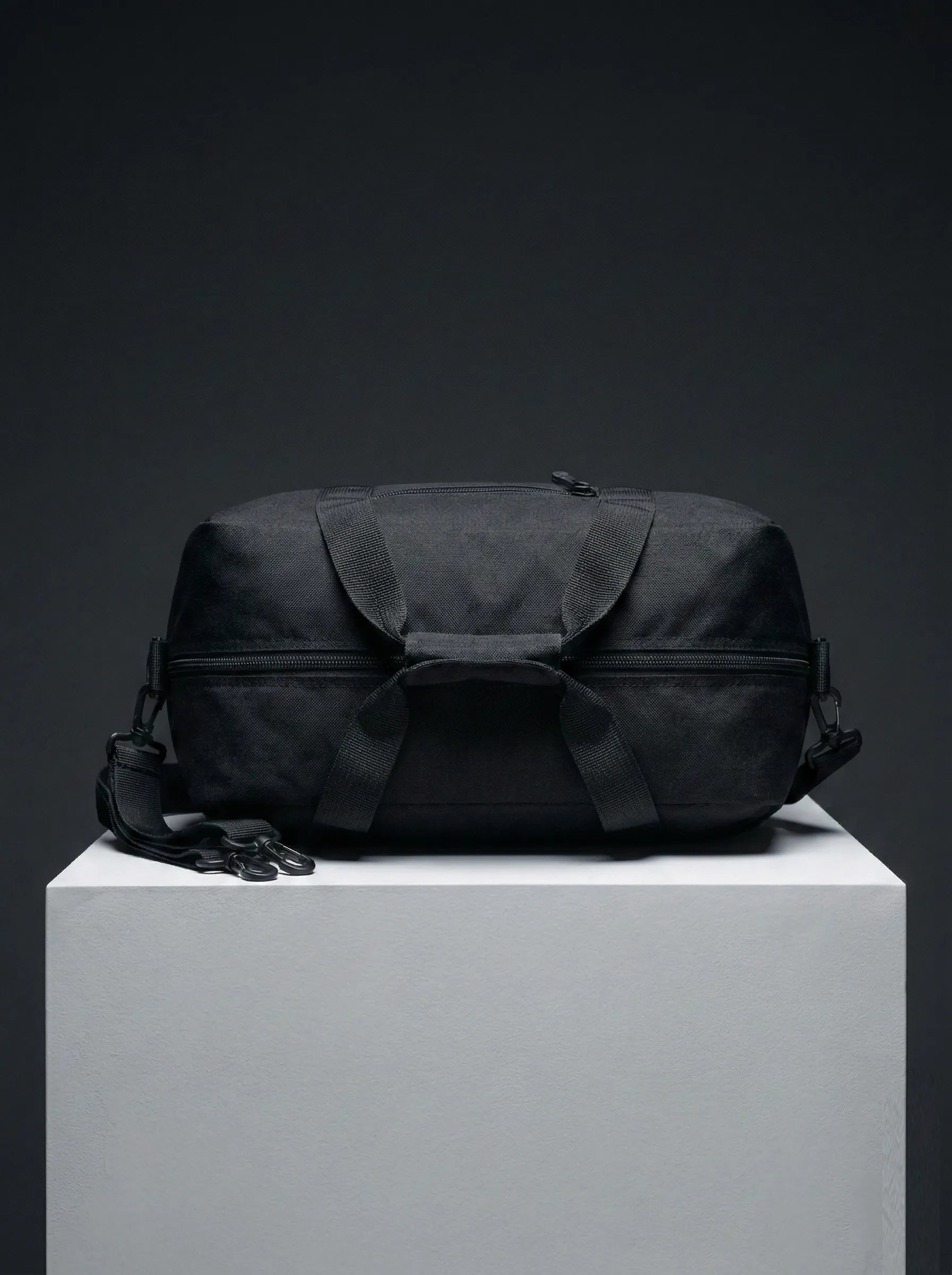 Top view of black EQ1 duffel bag featuring strong handles, zipper closure, and durable travel-ready structure on a white display platform.
