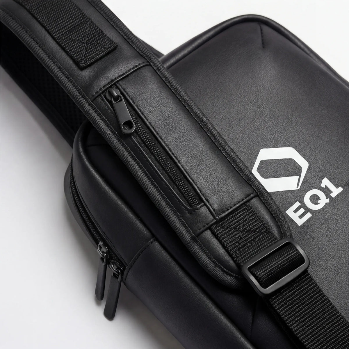 Close-up of black EQ1 sling bag strap with zipper pocket and adjustable buckle